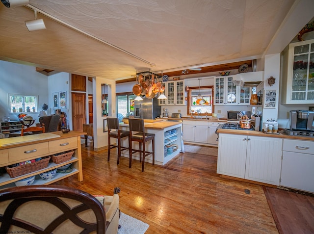 kitchen featuring white cabinetry, wooden counters, light hardwood / wood-style flooring, pendant lighting, and stainless steel appliances