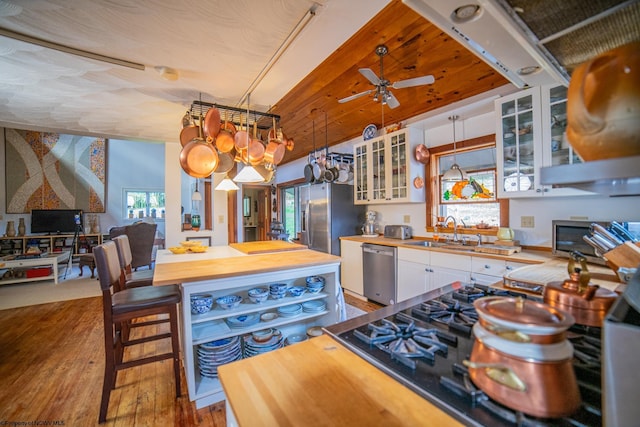 kitchen with sink, hardwood / wood-style flooring, stainless steel appliances, white cabinets, and decorative light fixtures