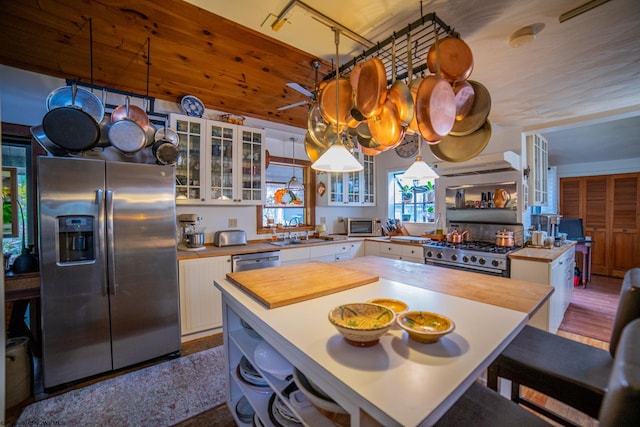 kitchen with a kitchen island, white cabinetry, sink, hanging light fixtures, and stainless steel appliances