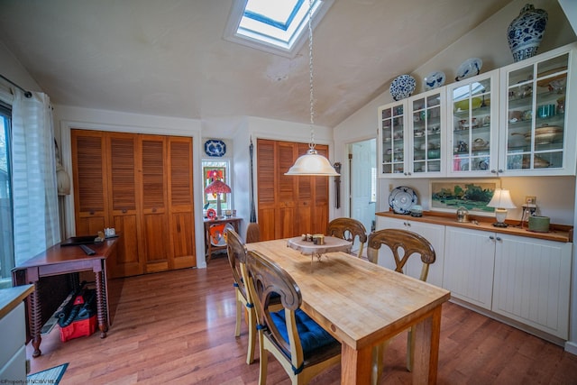 dining space with plenty of natural light, vaulted ceiling with skylight, and light hardwood / wood-style floors