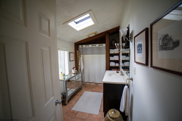 bathroom featuring vanity, curtained shower, and vaulted ceiling with skylight