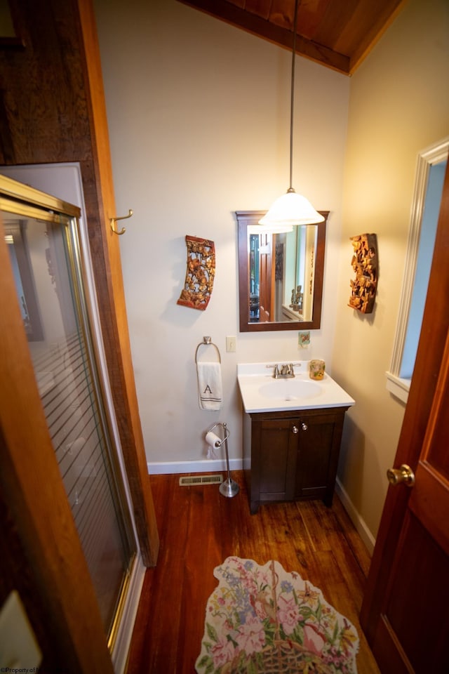 bathroom featuring wood-type flooring, a shower with door, and vanity