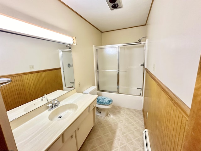 full bathroom featuring vanity, shower / bath combination with glass door, wooden walls, toilet, and baseboard heating