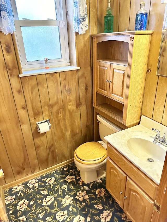 bathroom featuring wood walls, vanity, and toilet