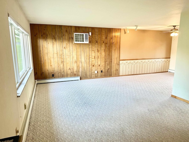 spare room featuring track lighting, ceiling fan, a baseboard heating unit, carpet floors, and wood walls