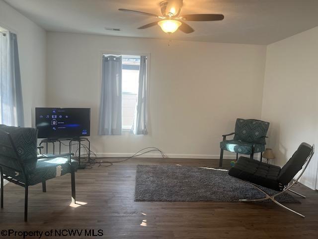 sitting room with dark wood-type flooring and ceiling fan