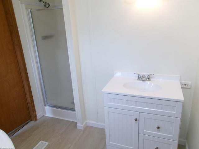 bathroom featuring vanity, visible vents, wood finished floors, and a stall shower