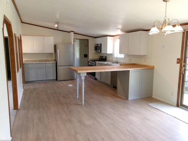 kitchen with a sink, appliances with stainless steel finishes, crown molding, light wood finished floors, and lofted ceiling