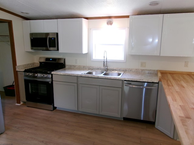 kitchen featuring a sink, wooden counters, light wood-style floors, and appliances with stainless steel finishes