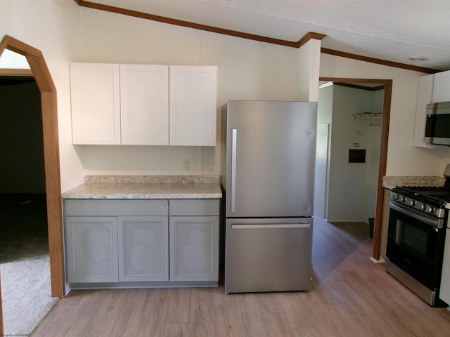 kitchen featuring light wood finished floors, stainless steel appliances, light countertops, and lofted ceiling