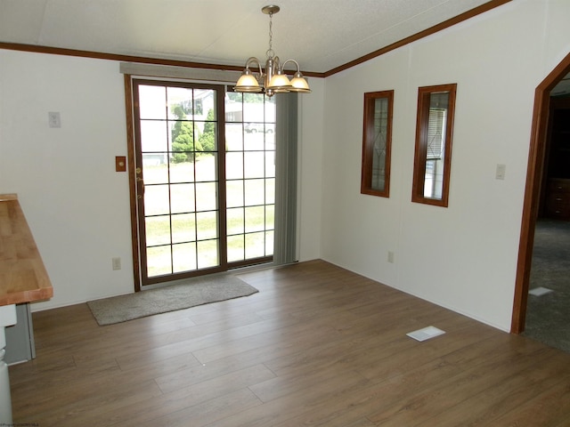 interior space featuring a healthy amount of sunlight, an inviting chandelier, lofted ceiling, and wood finished floors