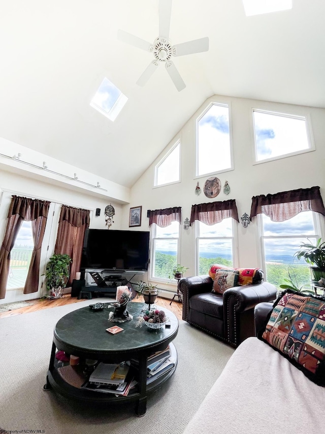 living room with ceiling fan, high vaulted ceiling, and a skylight