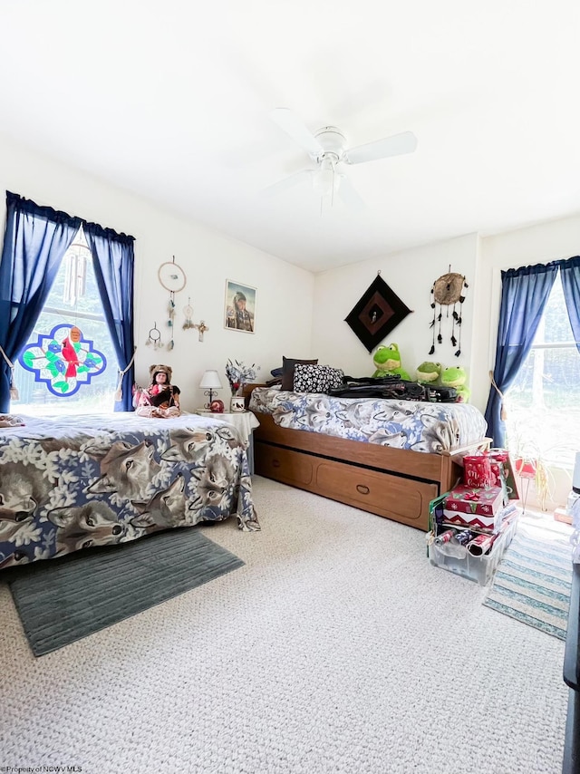 carpeted bedroom featuring multiple windows and ceiling fan