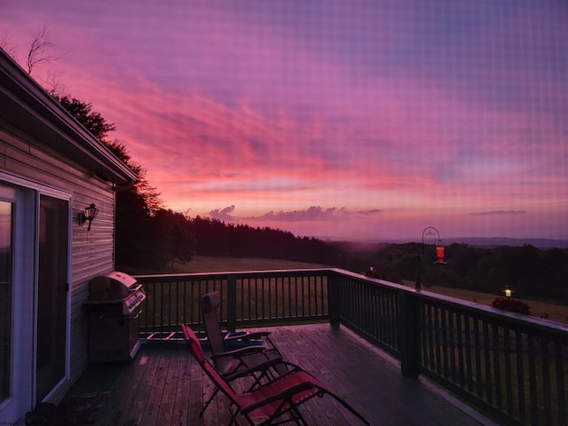 deck at dusk featuring a grill