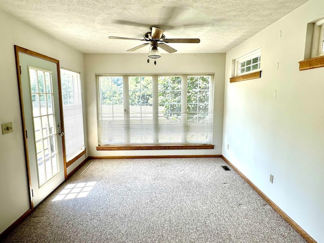 empty room featuring ceiling fan, carpet flooring, and a textured ceiling