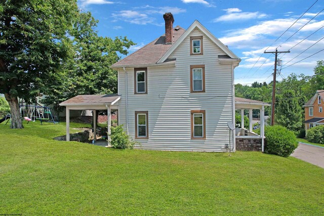 back of property featuring a playground and a yard