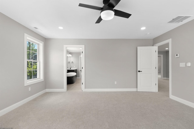 unfurnished bedroom with ensuite bathroom, ceiling fan, and light carpet