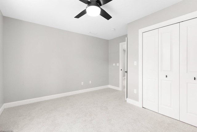 unfurnished bedroom featuring a closet, ceiling fan, and light colored carpet