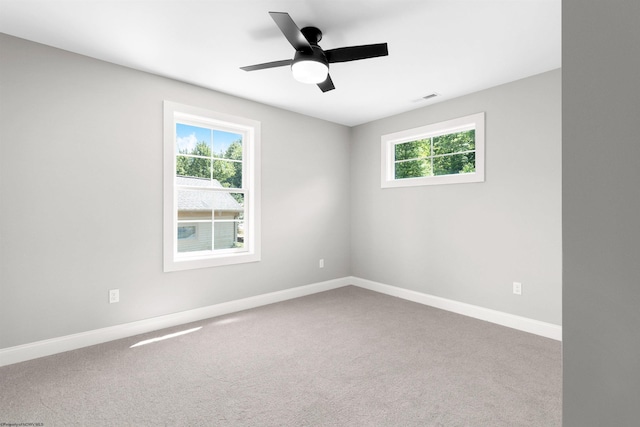 empty room featuring a wealth of natural light, carpet, and ceiling fan