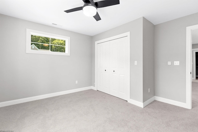 unfurnished bedroom featuring ceiling fan, a closet, and light carpet