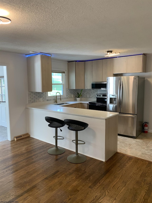 kitchen featuring kitchen peninsula, black electric range, sink, extractor fan, and stainless steel fridge with ice dispenser