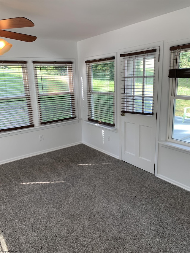 empty room with ceiling fan and dark colored carpet