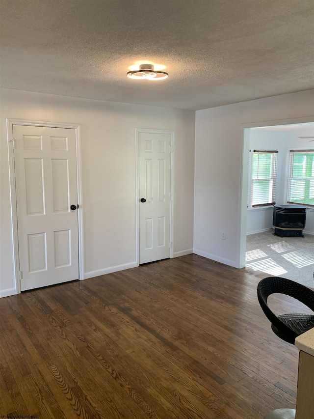 unfurnished room with dark wood-type flooring and a textured ceiling