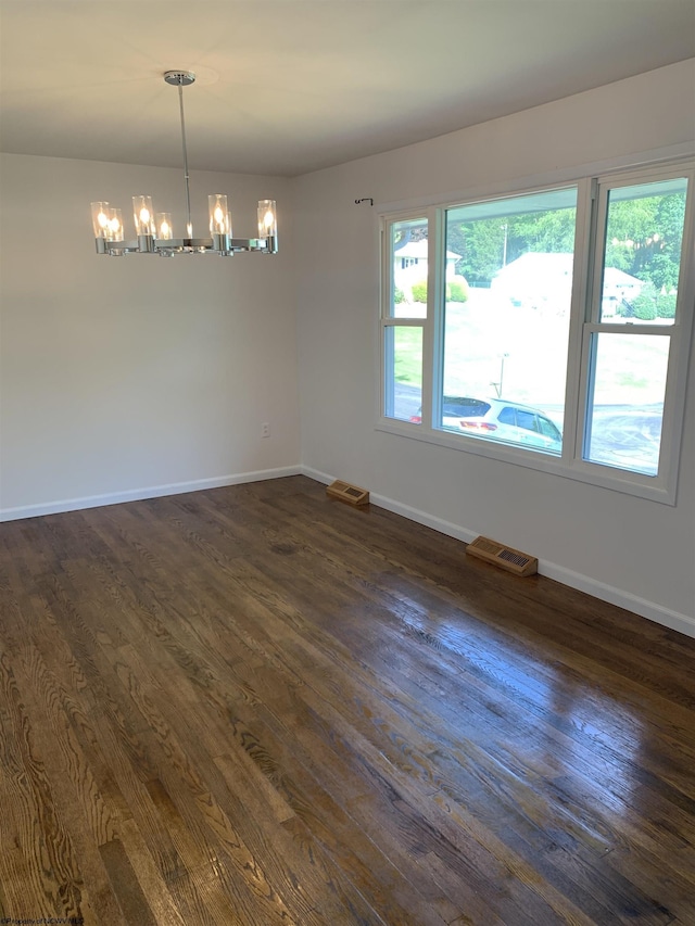 empty room featuring an inviting chandelier and dark hardwood / wood-style floors