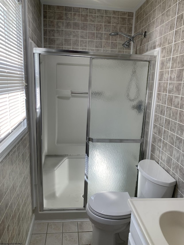 bathroom with toilet, an enclosed shower, tile walls, tile patterned flooring, and vanity