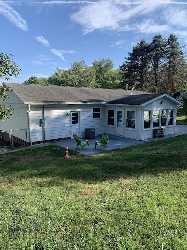 rear view of house with cooling unit, a lawn, and a patio