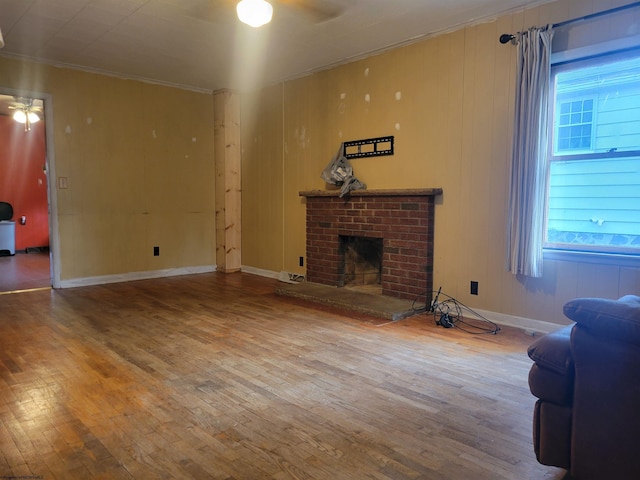 living room featuring crown molding, ceiling fan, hardwood / wood-style floors, and a brick fireplace