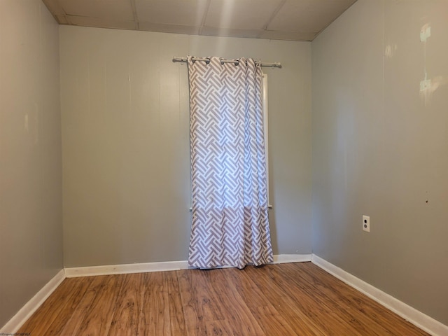 empty room with a paneled ceiling and wood-type flooring