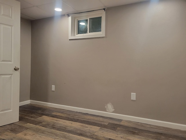 spare room with dark hardwood / wood-style flooring and a drop ceiling