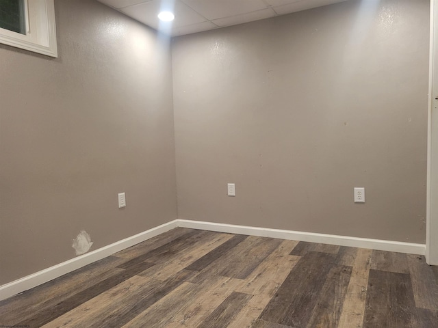 unfurnished room with a paneled ceiling and wood-type flooring