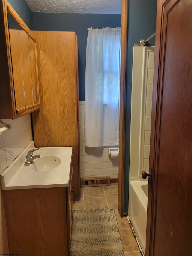 bathroom featuring vanity, tile patterned flooring, a textured ceiling, and tile walls