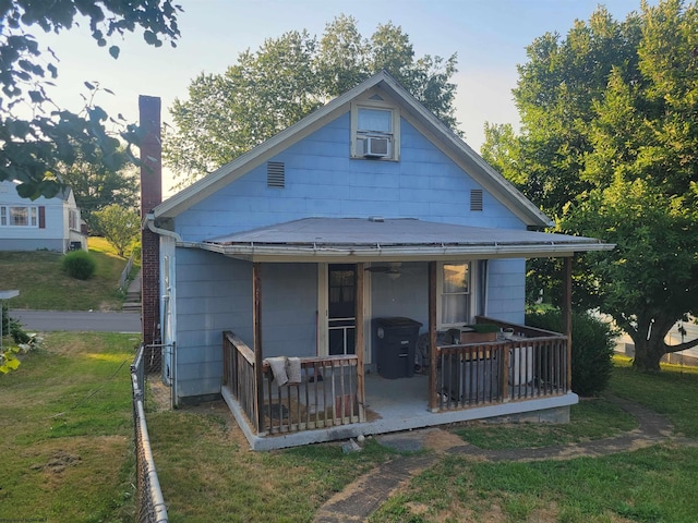 rear view of property with a porch, cooling unit, and a lawn