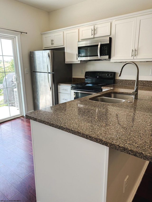 kitchen featuring white cabinetry, sink, dark stone countertops, stainless steel appliances, and dark hardwood / wood-style floors