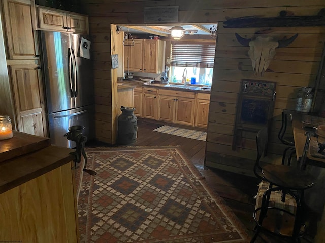 kitchen with stainless steel fridge, sink, dark hardwood / wood-style flooring, and wooden walls