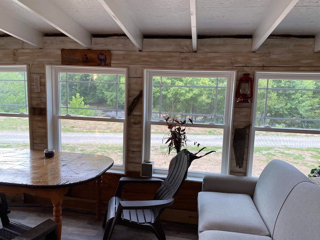 dining space featuring wood walls and beamed ceiling