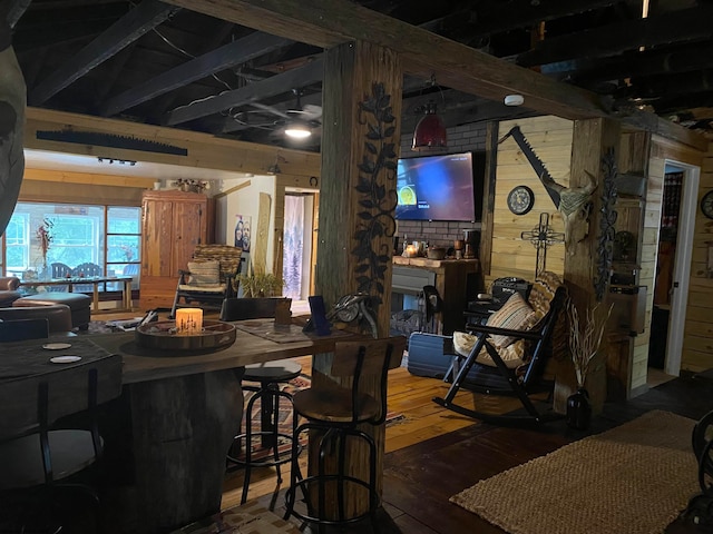 dining space featuring beam ceiling, hardwood / wood-style flooring, and wooden walls