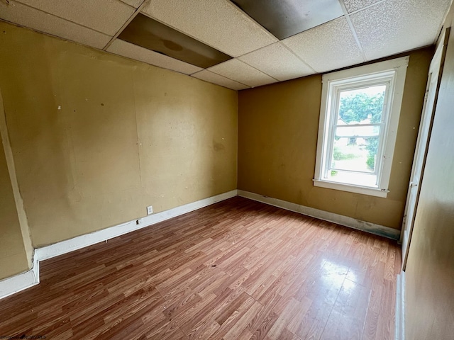 spare room with a drop ceiling and hardwood / wood-style floors