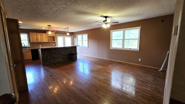 unfurnished living room with a textured ceiling, dark hardwood / wood-style flooring, sink, and ceiling fan