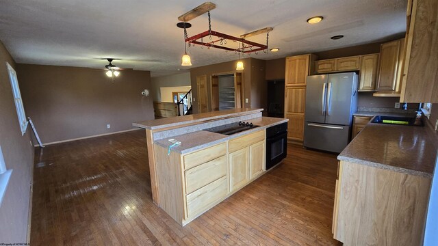 kitchen with black appliances, hardwood / wood-style floors, sink, a center island, and ceiling fan