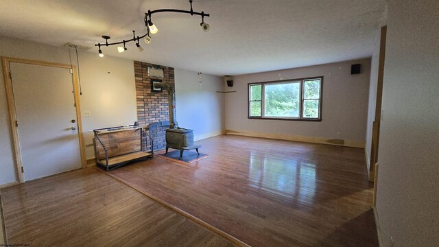 living room with a textured ceiling, track lighting, hardwood / wood-style floors, and a wood stove