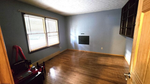 interior space with a textured ceiling and hardwood / wood-style flooring