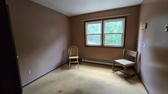 unfurnished room with a textured ceiling, a baseboard heating unit, and concrete floors