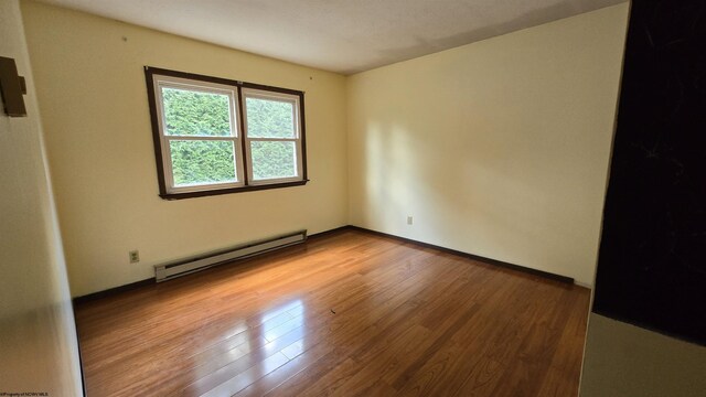 empty room with light hardwood / wood-style flooring and baseboard heating