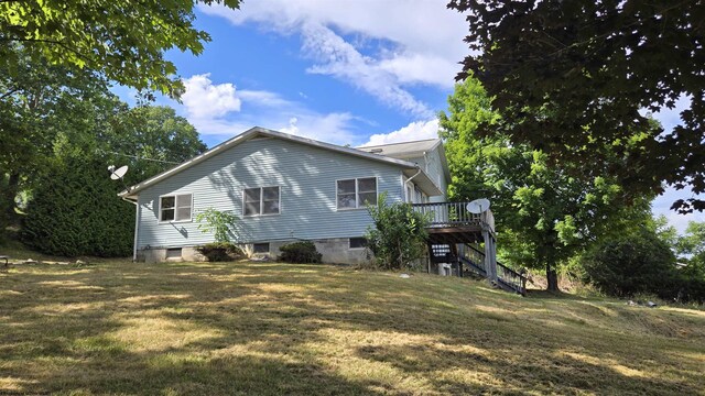 view of home's exterior featuring a wooden deck and a lawn