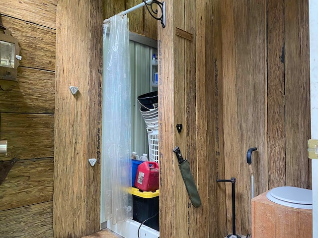 bathroom featuring wood walls and toilet