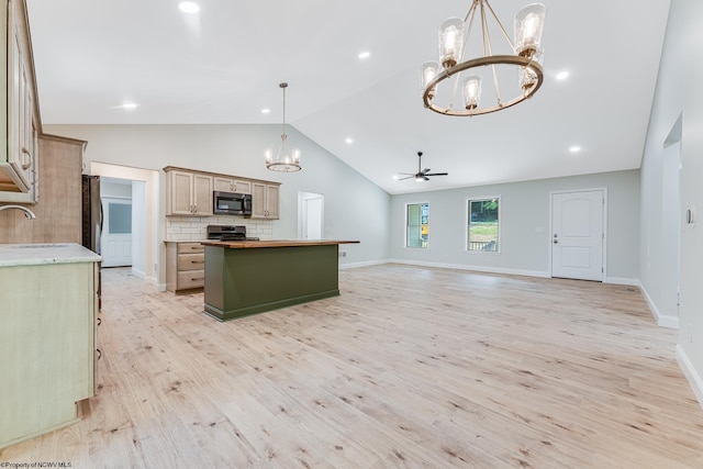 kitchen featuring hanging light fixtures, appliances with stainless steel finishes, ceiling fan with notable chandelier, light hardwood / wood-style floors, and backsplash